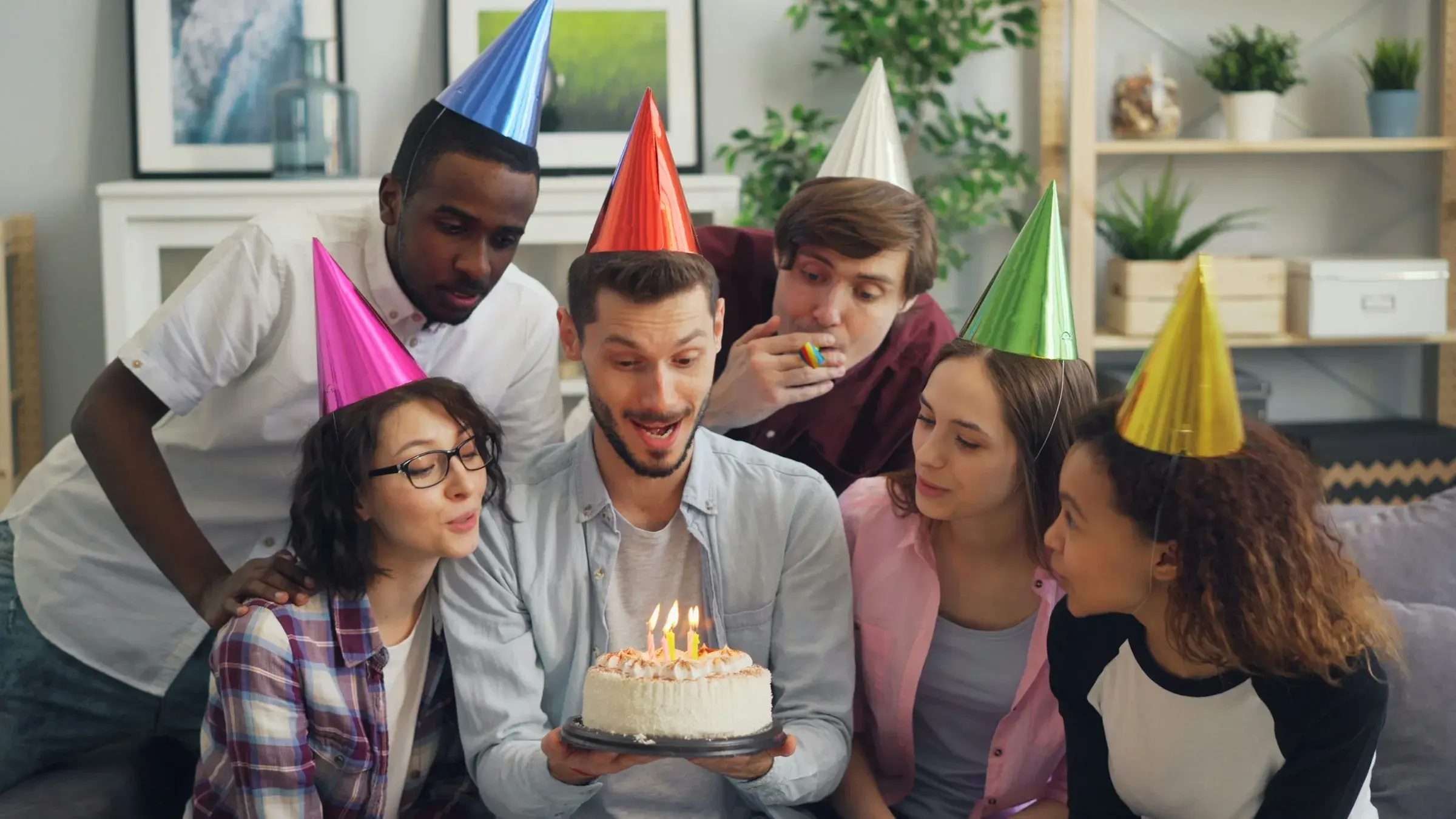 Un gruppo di amici con i cappellini da festa intorno alla torta di compleanno