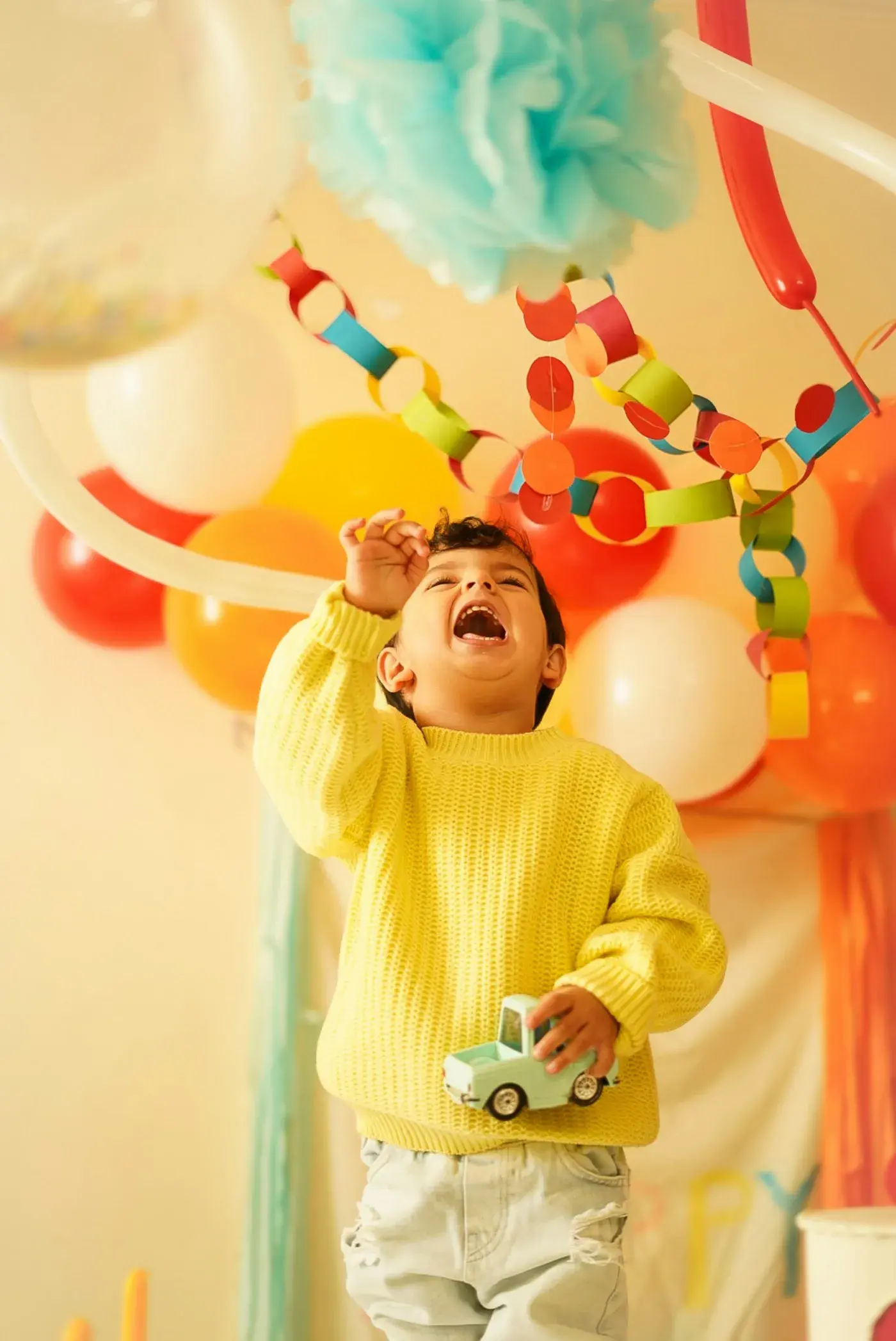 Un bambino ride sotto palloncini e festoni colorati